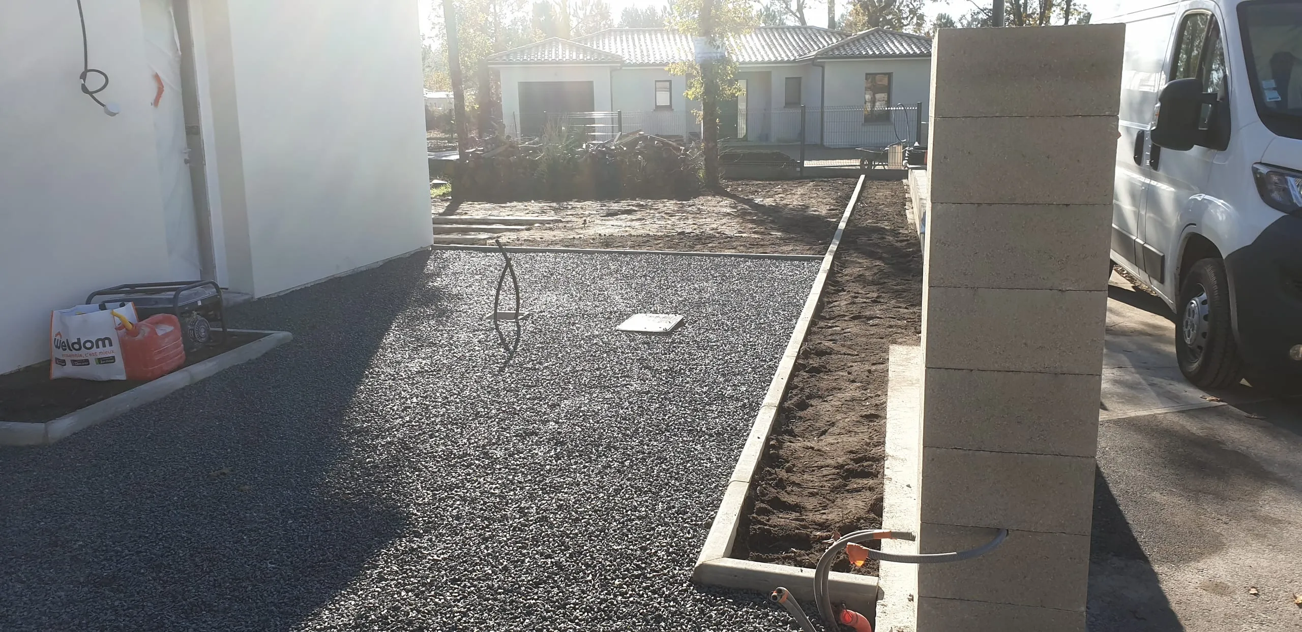 Parking en gravier gris avec pilastres maçonnés, aménagement professionnel