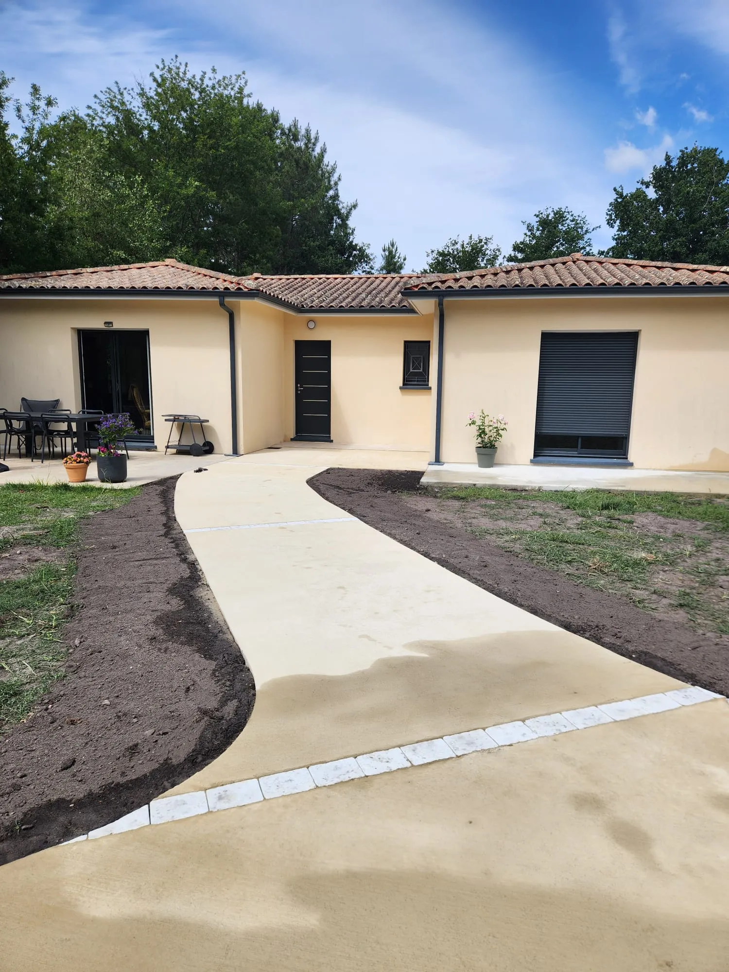 Belle allée en béton pierre balayé menant à une maison en tuiles romanes