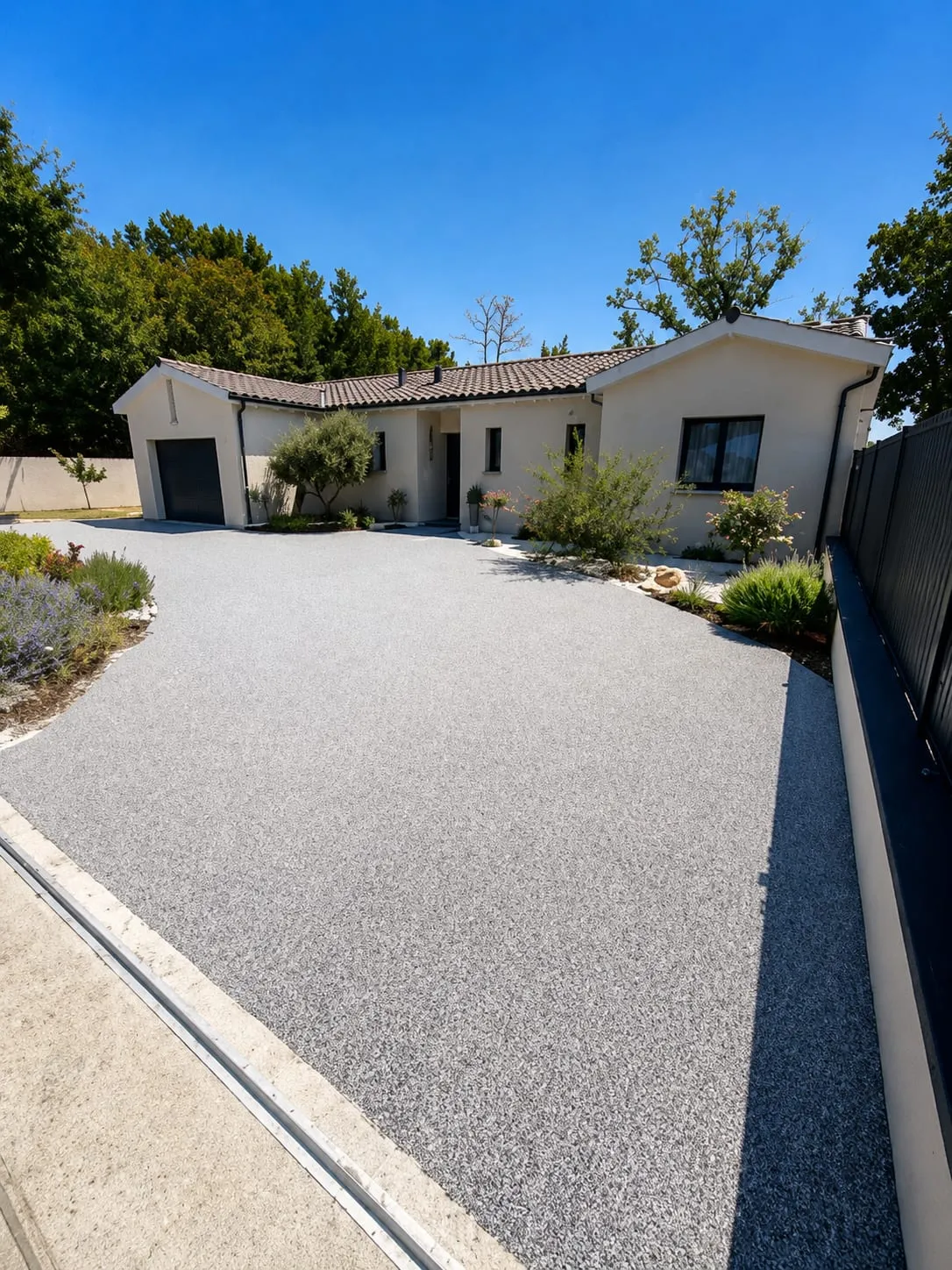 Jardin aménagé avec graviers gris et rouges, dalles de cheminement et bordures claires