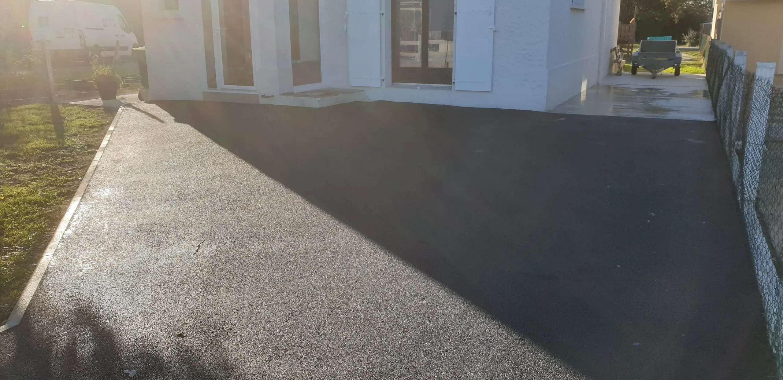 Enrobé bitumineux noir posé devant un pavillon, cour nette et carrossable