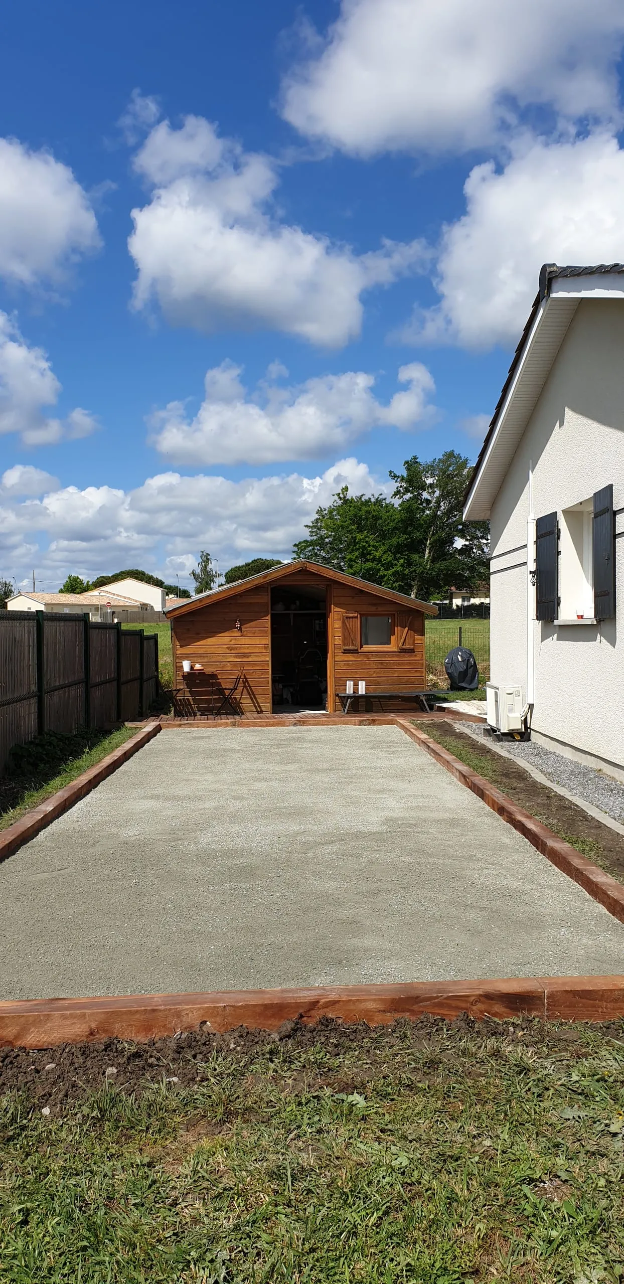 Jardin aménagé avec clôture en bambou et abri de jardin en bois en arrière-plan