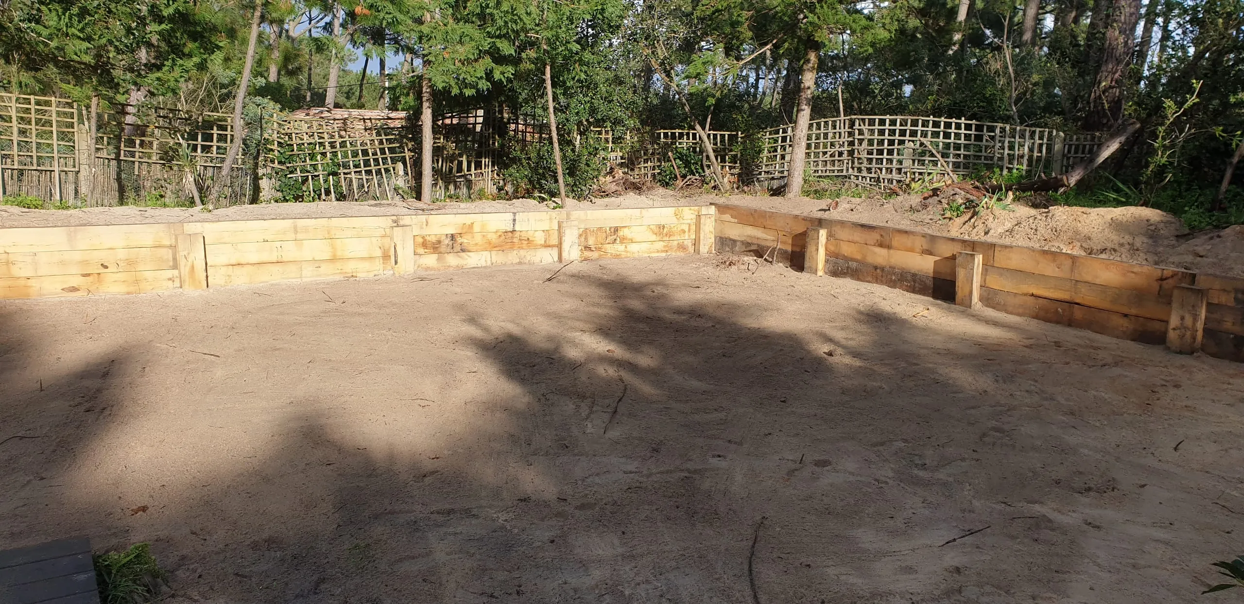 Terrain de pétanque avec mur de soutènement en rondins bois, sable fin