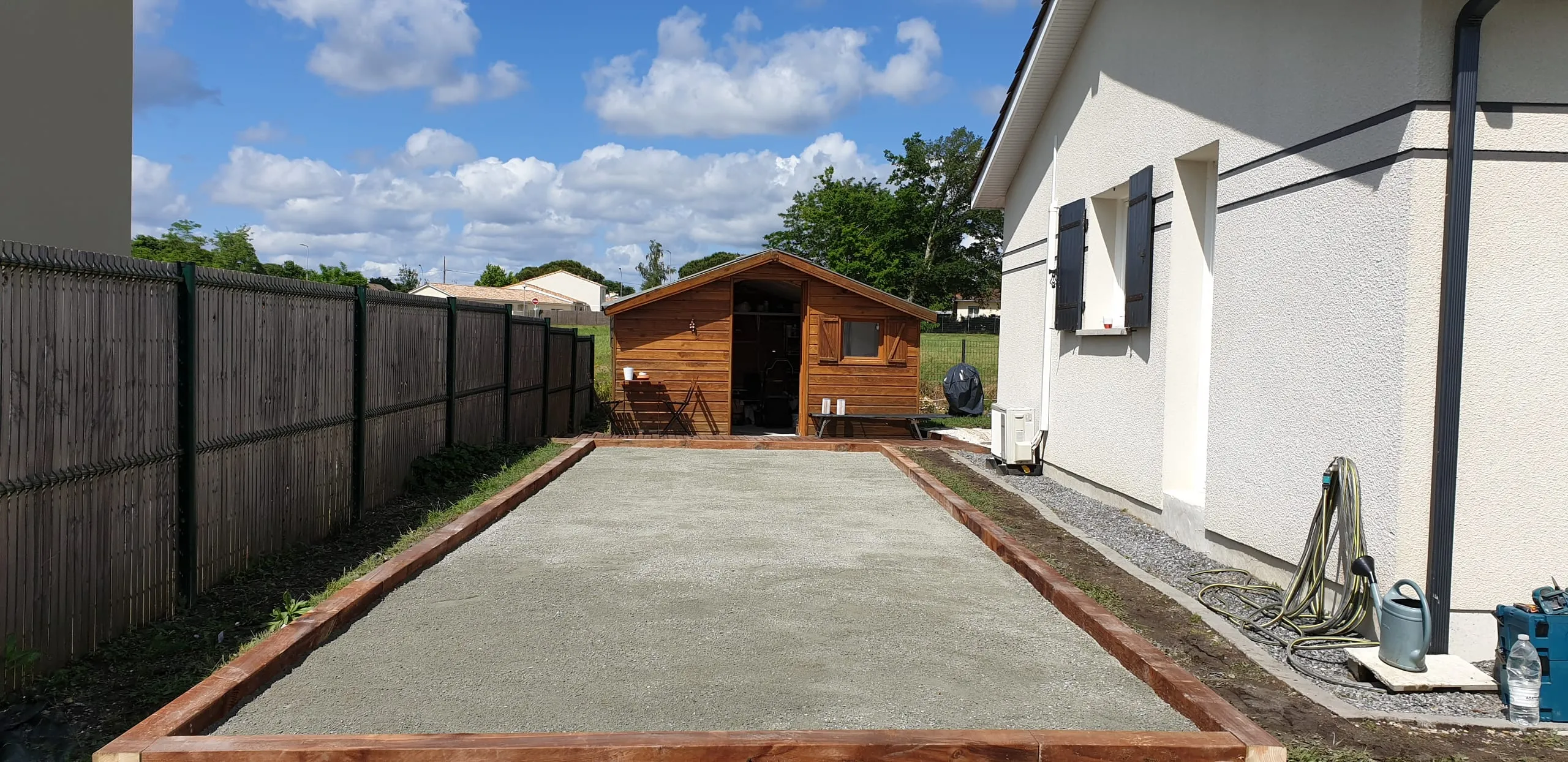 Terrain de pétanque finalisé avec cadre bois, ciel bleu médocain